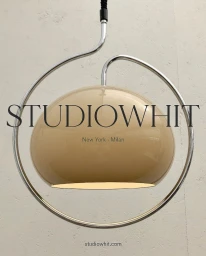 Beige dome pendant lamp framed by a circular chrome tube with Studio Whit typography overlay against an off-white wall.