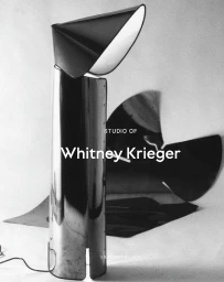 Sculptural polished metal floor lamp with a folded geometric shade against a neutral studio background.