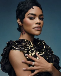 Teyana Taylor posing with hand on chest wearing a black ruffle top with gold trim against a dark blue background.