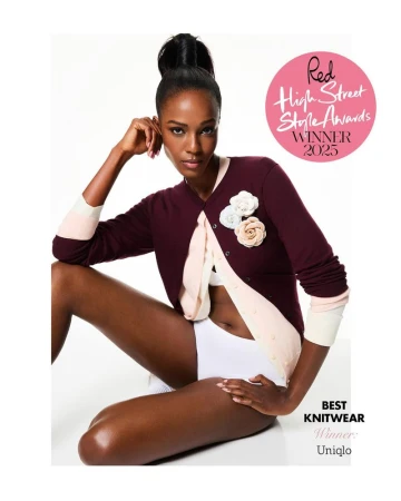 Leila Nda seated in a layered burgundy and pale pink cardigan with floral pins against a white studio background.