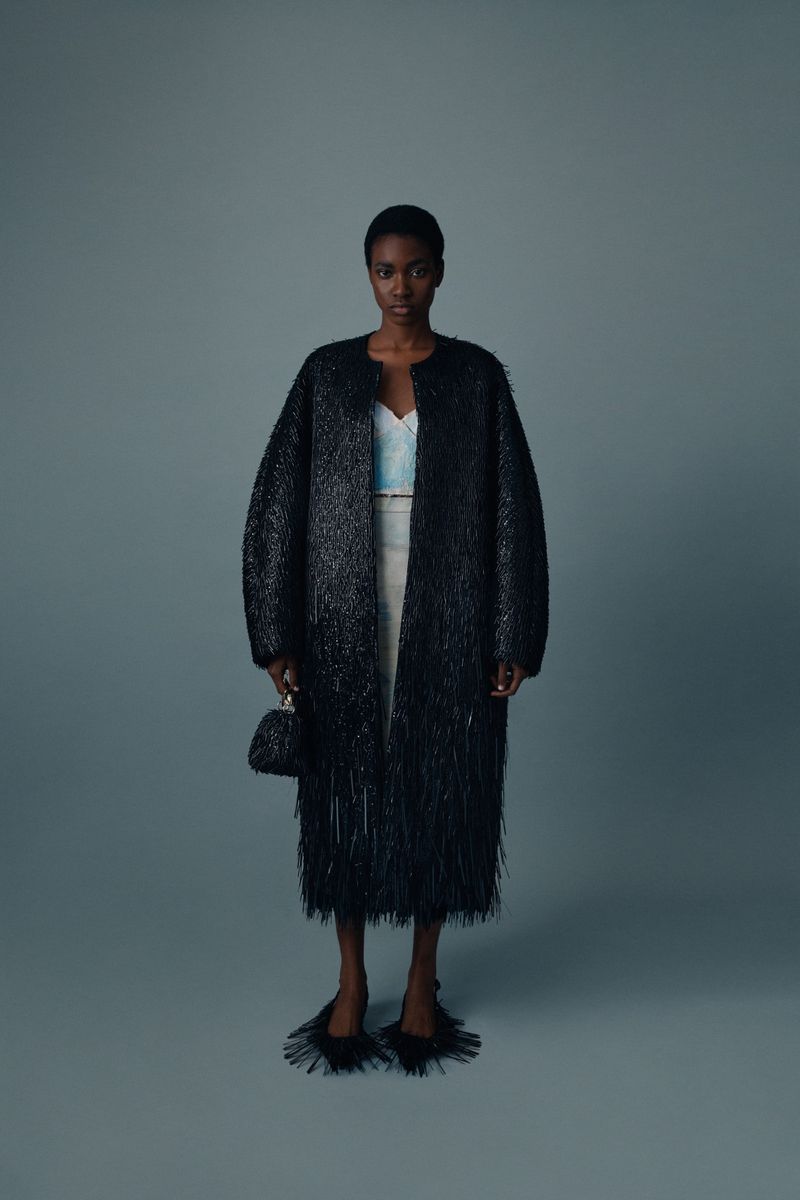 Elegant Black Woman in Striking Coat: Full-length portrait of a fashion model wearing a distinctive black coat and accessories in studio.