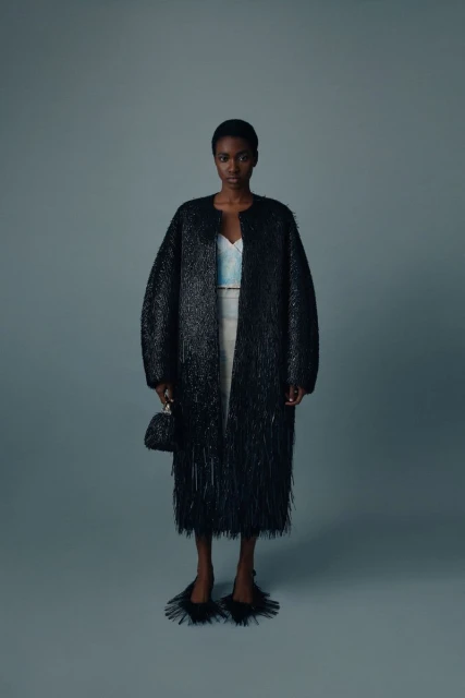 Elegant Black Woman in Striking Coat: Full-length portrait of a fashion model wearing a distinctive black coat and accessories in studio.