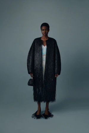 Elegant Black Woman in Striking Coat: Full-length portrait of a fashion model wearing a distinctive black coat and accessories in studio.