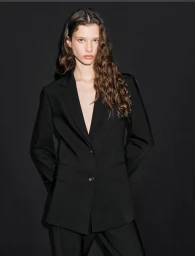 Model in black blazer against a dark background for Massimo Dutti Summer 2025 campaign, photographed by Sara Moràn.