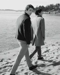 Two male models walking along a sandy shoreline wearing tailored coats for Tiger of Sweden