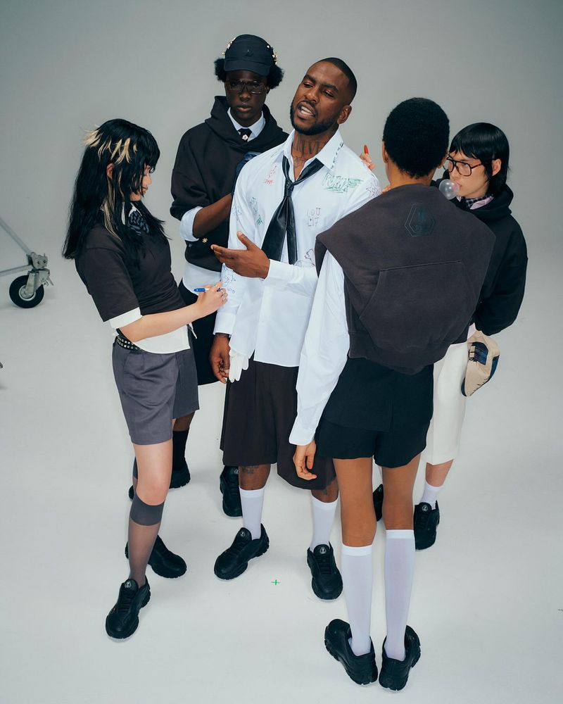 Fashion-forward group poses in a photo studio, showcasing contemporary streetwear with a blend of casual and avant-garde styles against a white backdrop.