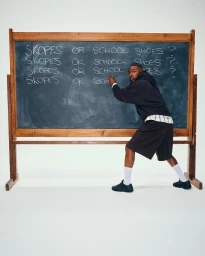 Skepta writing on a large blackboard in front of a white wall for the Puma x Skepta Skope campaign