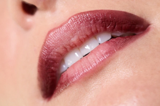 Close-up macro shot of dark plum lipstick on lips with visible white teeth for Heather Kamesky by Love Want