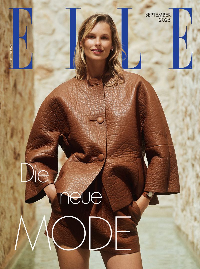 Fashion magazine cover featuring a blonde woman in a brown leather jacket and shorts standing in a sunlit outdoor setting.