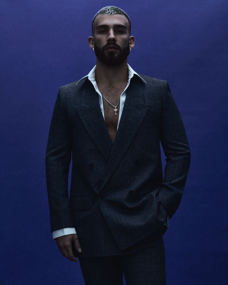 Portrait of handsome adult male with short hair and beard in dark suit against a purple background in studio lighting. Fashion shoot.