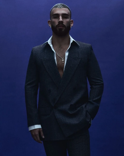 Portrait of handsome adult male with short hair and beard in dark suit against a purple background in studio lighting. Fashion shoot.
