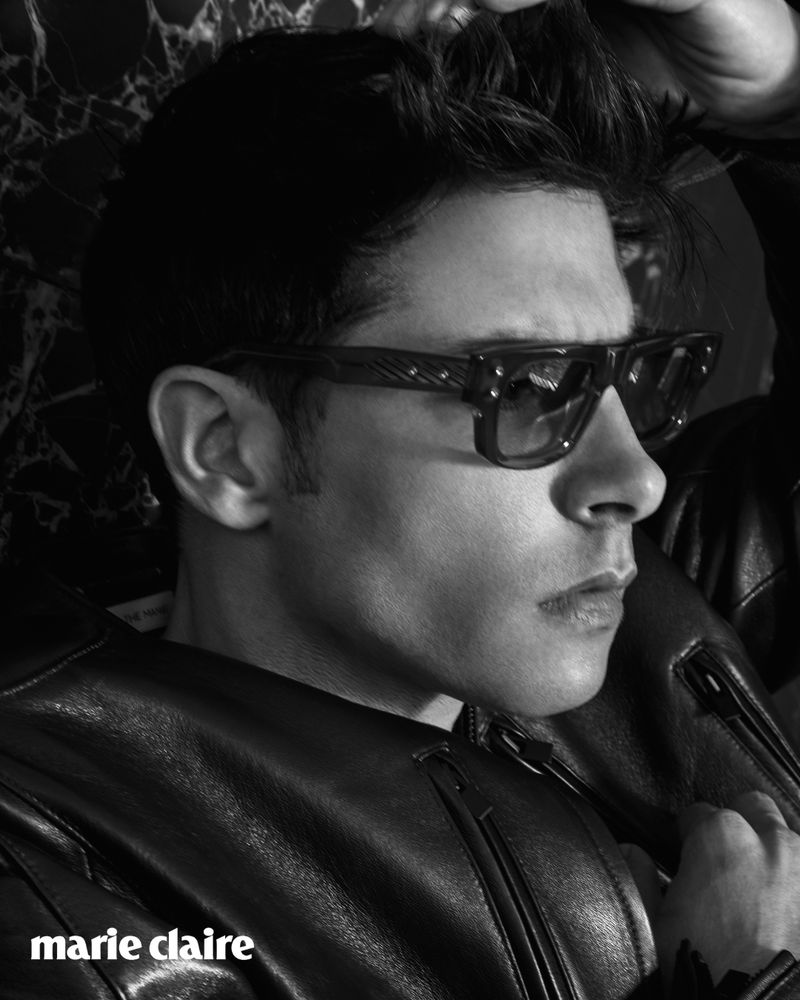 Monochrome portrait of a man in sunglasses and a leather jacket, styled for a high-fashion magazine shoot. Dark, moody, and high-contrast.