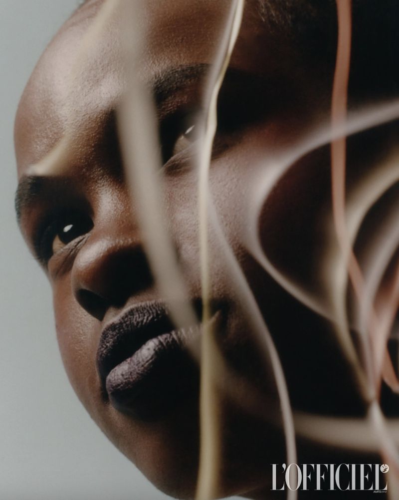 Close-up portrait of a Black adult woman with dark lipstick, captured in a photo studio with soft lighting and artistic lines.