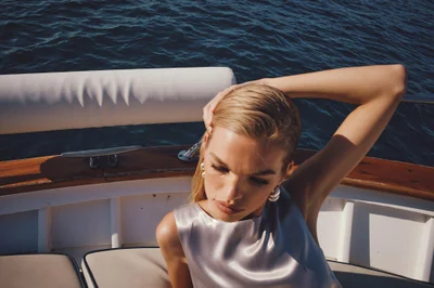 Model Daphne Groeneveld wearing a silver top and pearl earrings on a boat for VRG GRL Fall '24 Campaign photographed by Simon Lekias.