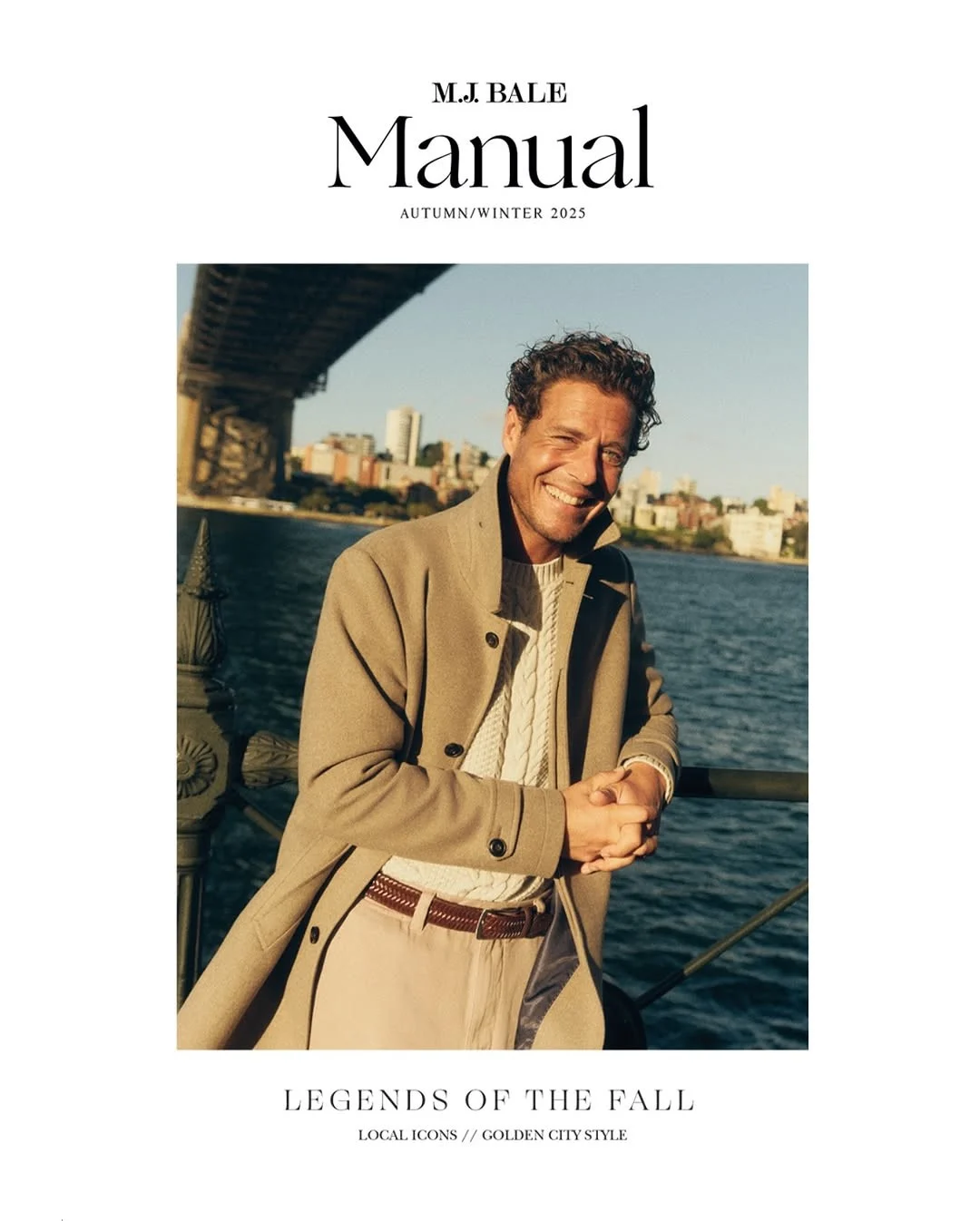 Man in tan coat smiles near water. Autumn/Winter 2025 fashion advertisement featuring bridge, buildings, and bright sunlight backdrop.