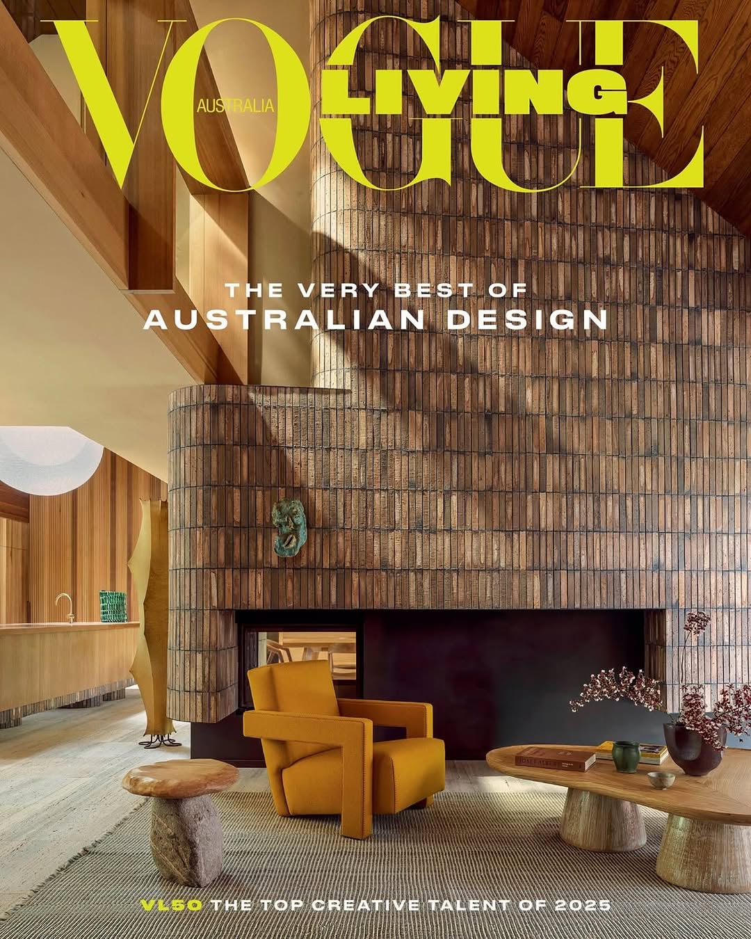Vogue Living Australia cover featuring a stylish living room with brick wall, yellow armchair, stone tables, and a modern interior design.