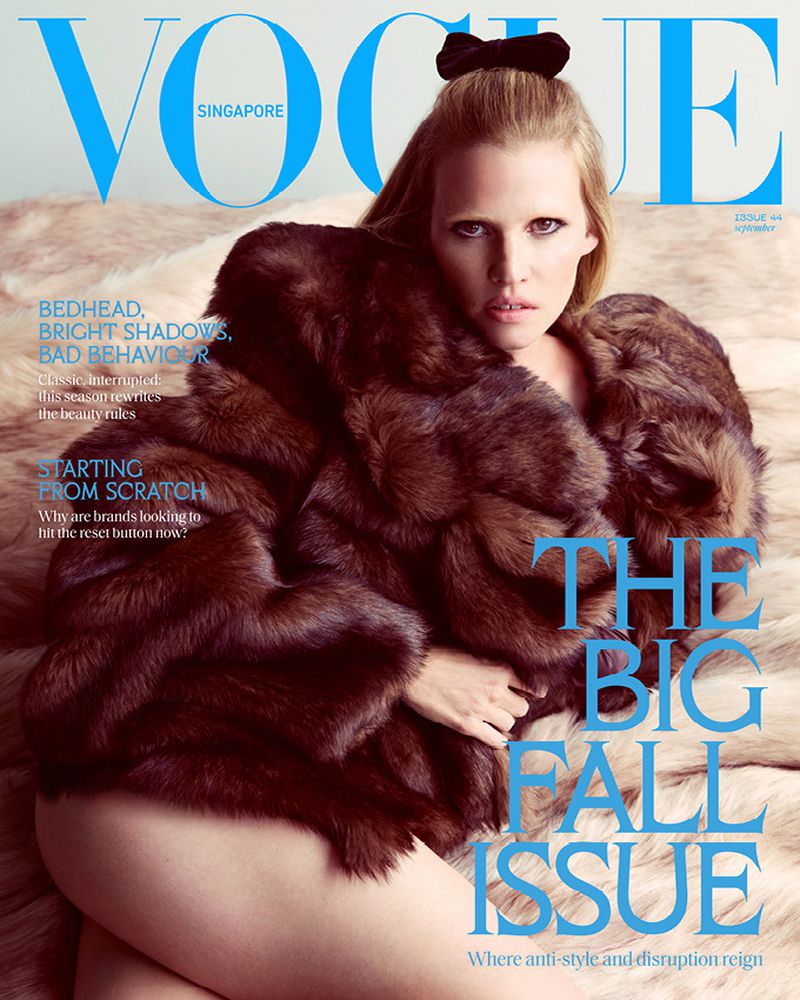 Vogue Singapore magazine cover featuring a blond model in a fur coat against a neutral backdrop, with blue text overlay.