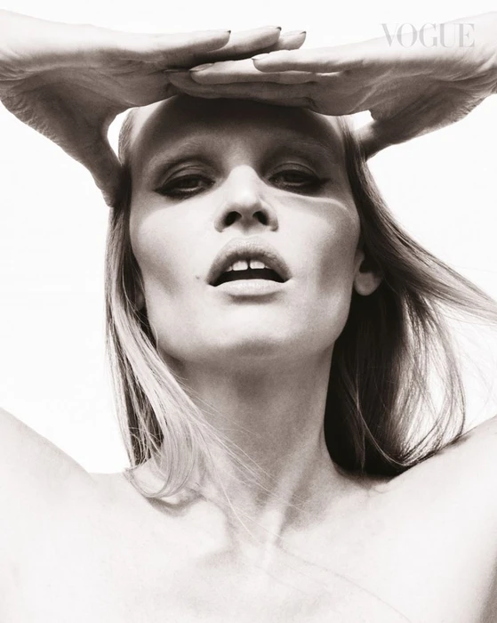 Model Lara Stone holding her hands above her forehead against a plain white background for Vogue Singapore