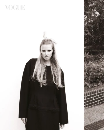 Model Lara Stone wearing a black coat and hair accessory in a monochrome fashion editorial for Vogue Singapore.