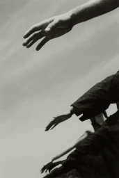 Multiple hands and arms reaching upward against a pale clouded sky background