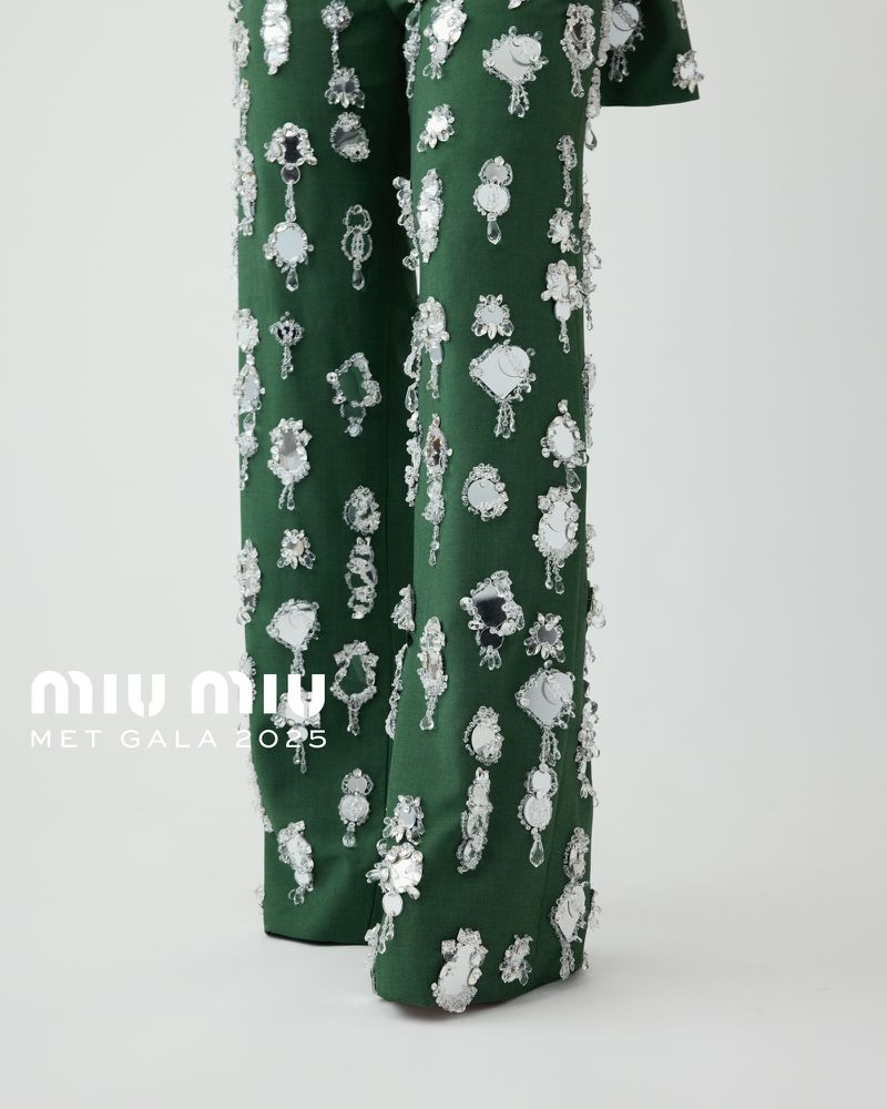 Close-up of green pants with decorative silver embellishments, studio lighting, and fashion-forward design.