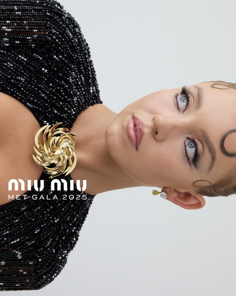 Headshot of a fair-skinned young adult woman with subtle makeup and decorative hair accessories, wearing a beaded black dress.