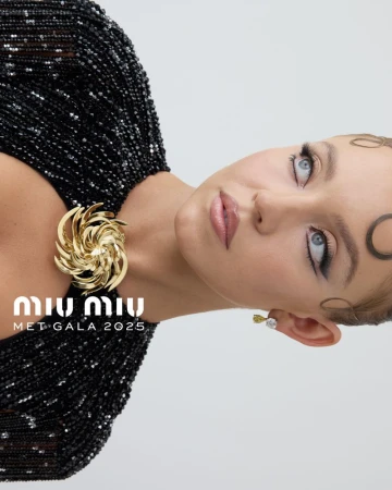 Headshot of a fair-skinned young adult woman with subtle makeup and decorative hair accessories, wearing a beaded black dress.