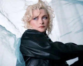 Alison Goldfrapp wearing an oversized black leather jacket framed by flowing sheer light blue fabric.