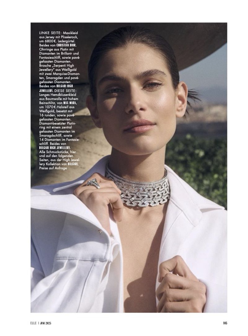 Close-up of a brunette woman wearing an elegant white jacket and diamond choker necklace, showcasing fine jewelry and fashion editorial style.