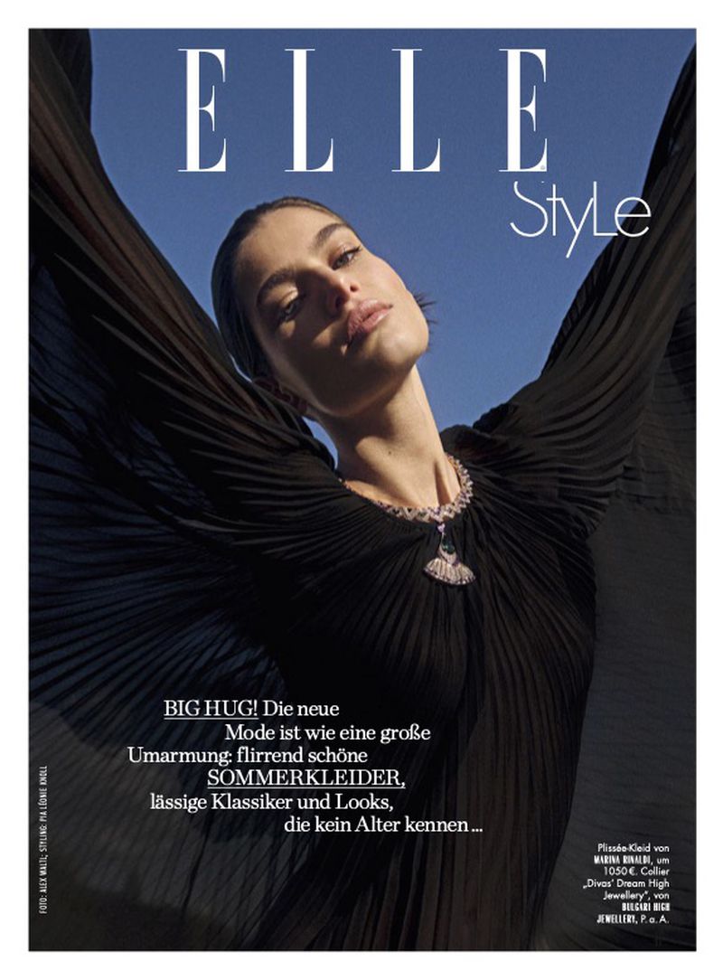 Elle Style magazine cover featuring a woman wearing a black gown and necklace, posing with arms raised against a blue sky backdrop.