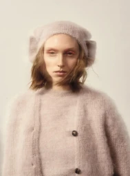 Model wearing a fuzzy blush pink knit cardigan and matching beret against a pale neutral background.