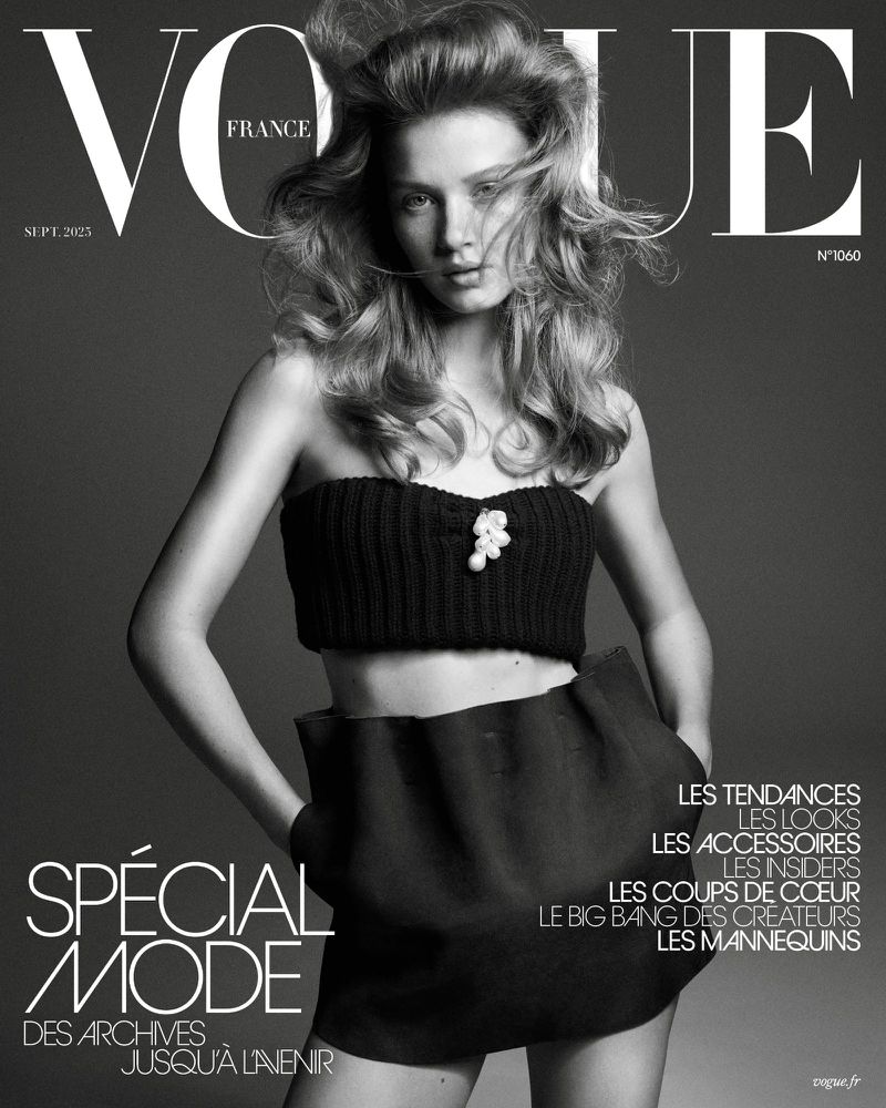 Vogue France cover featuring a woman with wavy blonde hair wearing a black strapless top and short skirt against a grey background.