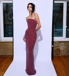 Model Paulina Pitsikalis posing in a strapless glittery gown against a white sweep background for Salih Balta SS25