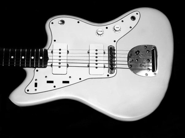 Electric guitar with a white body and black fretboard shown in a studio shot against a black background with clear volume and tone knobs.