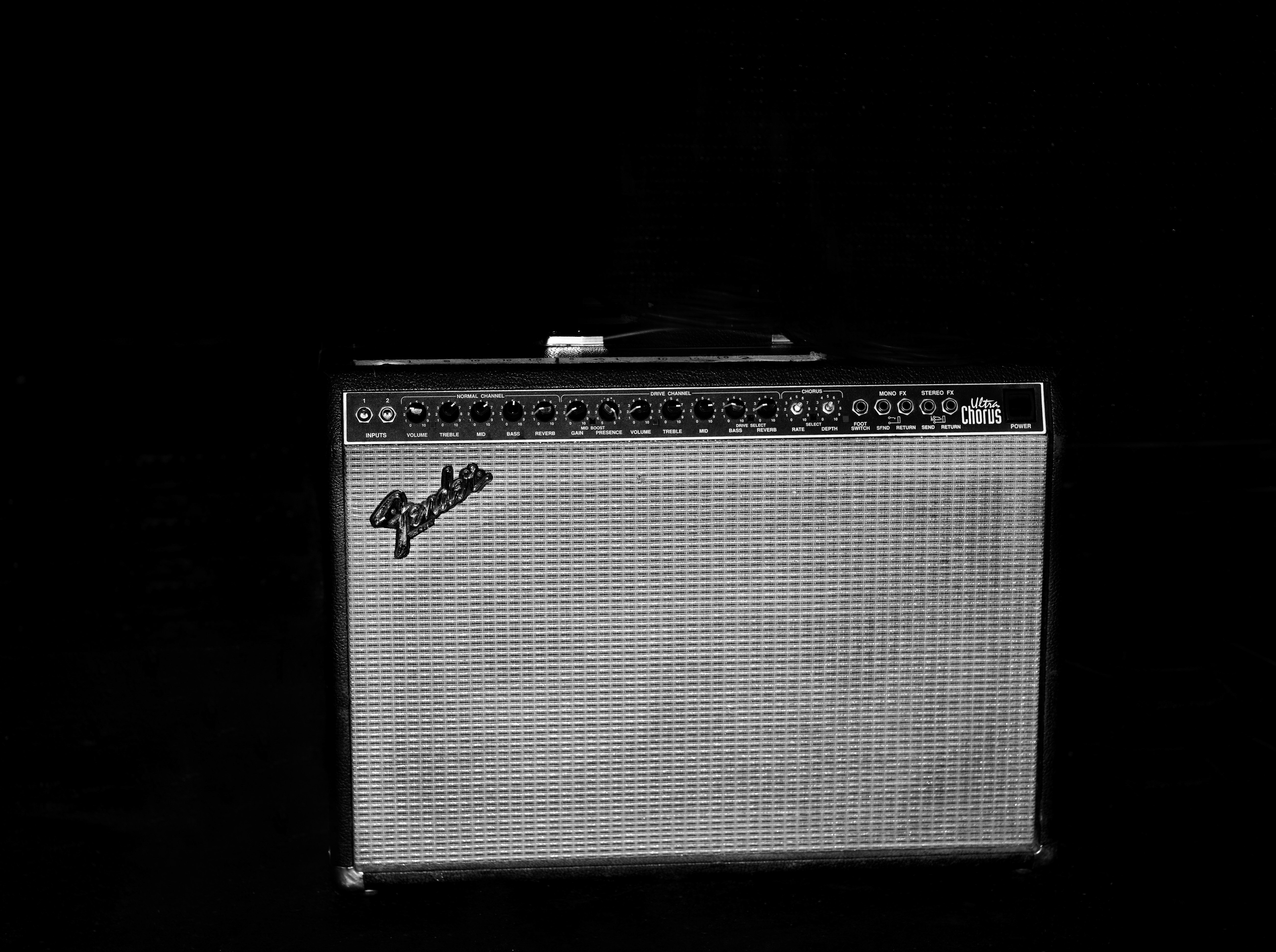 Black and white photo of a vintage Fender Ultra Chorus guitar amplifier with visible controls, speaker grill, and the Fender logo.