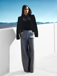 Woman in black jacket and grey trousers standing on a rooftop against a distant mountainous horizon by Cameron Krone for New York Times.