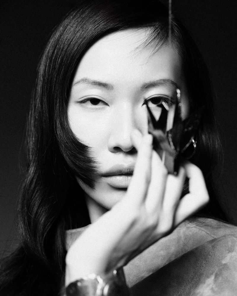 Monochrome portrait of an Asian female model with short dark hair holding a geometric object in a studio setting, artistic expression.