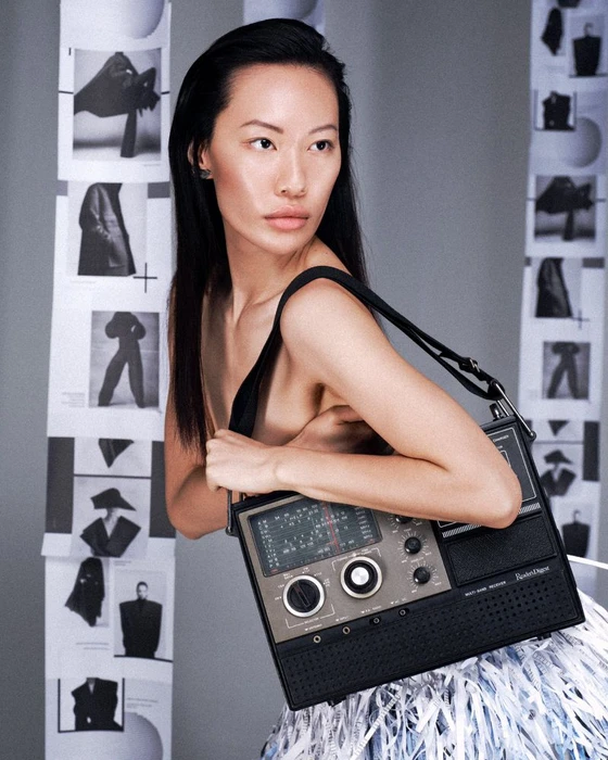 Asian female model wearing a black top holding a vintage radio against a grey seamless studio background with vertical photo strips.