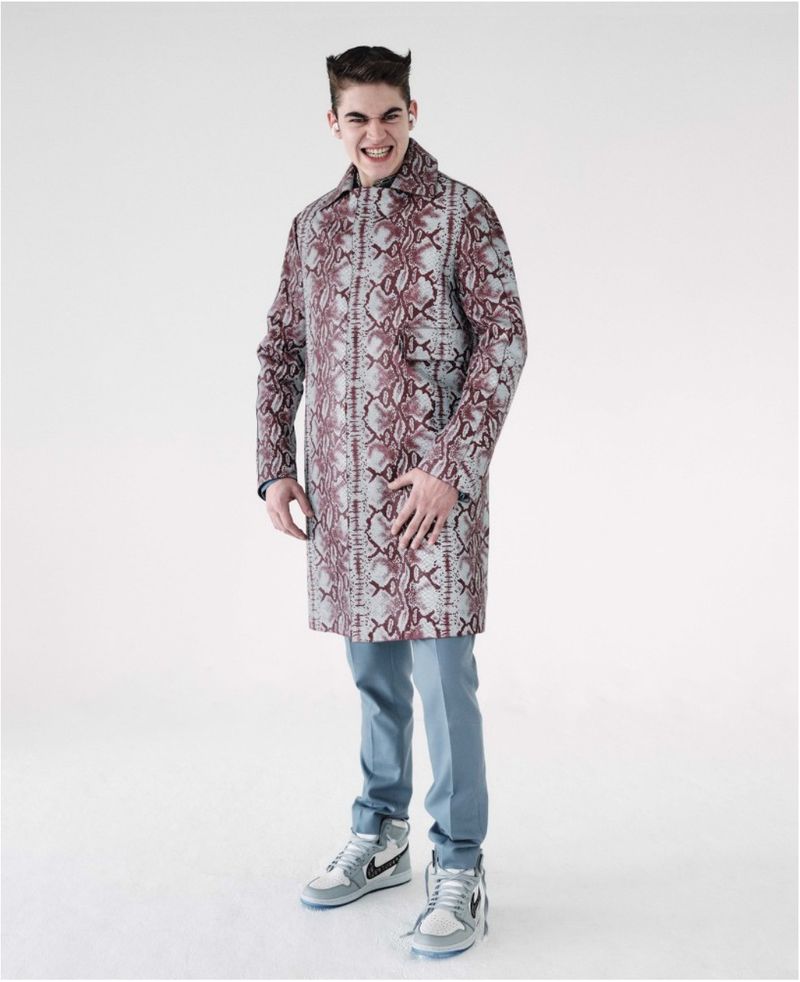 Hero Fiennes Tiffin wearing a patterned coat and light blue trousers against a plain white background for GQ Australia.