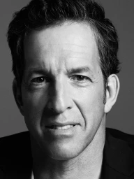 Close-up black and white portrait of a middle-aged man with dark hair looking directly at the camera.