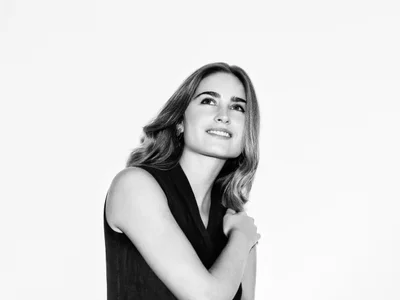 Monochrome portrait of Lauren Bush by photographer Cameron Krone, looking up with a gentle smile against a plain white background.