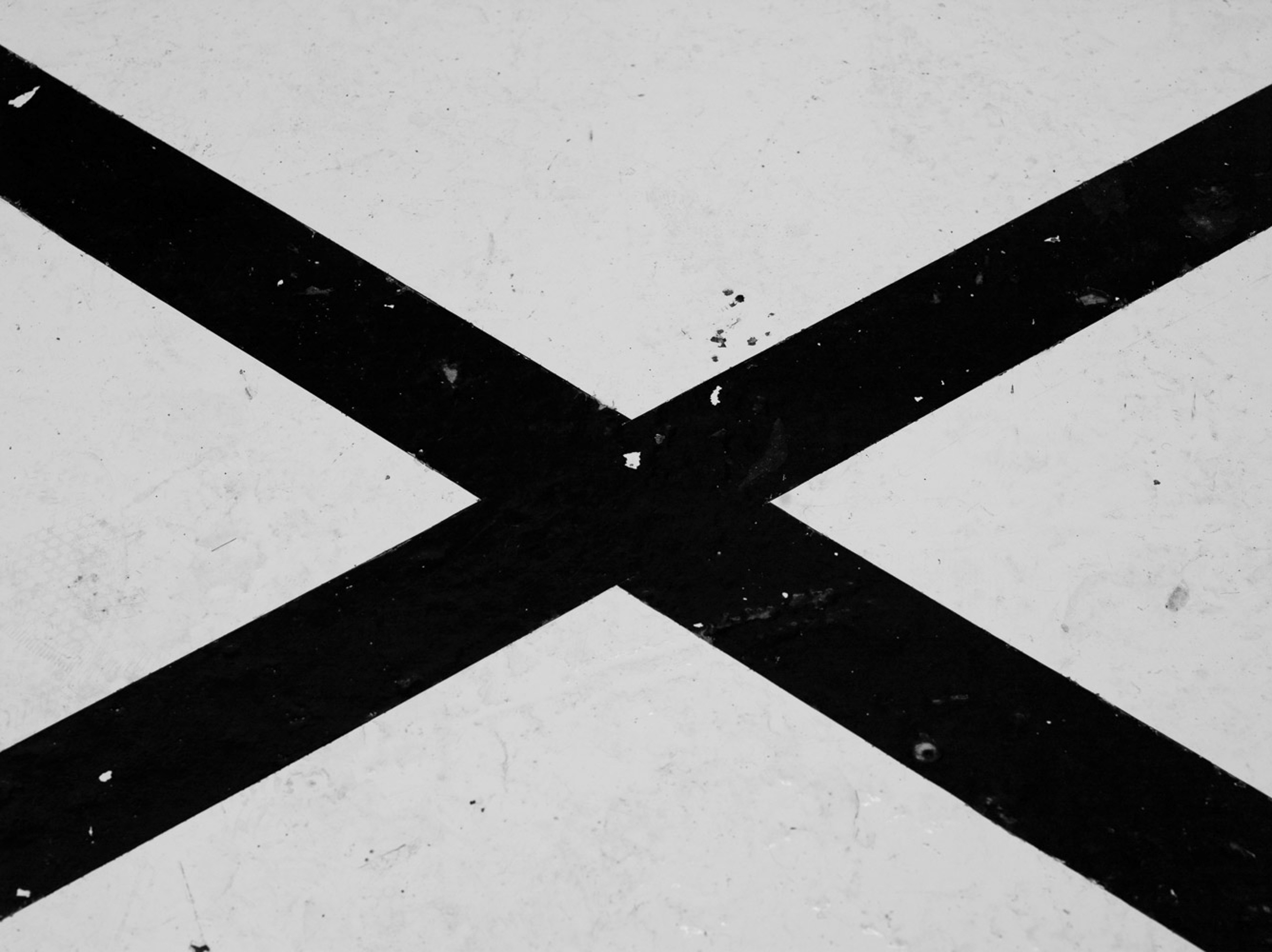 Abstract black and white image featuring a bold black X shape crossing a textured white surface. Minimalist design.
