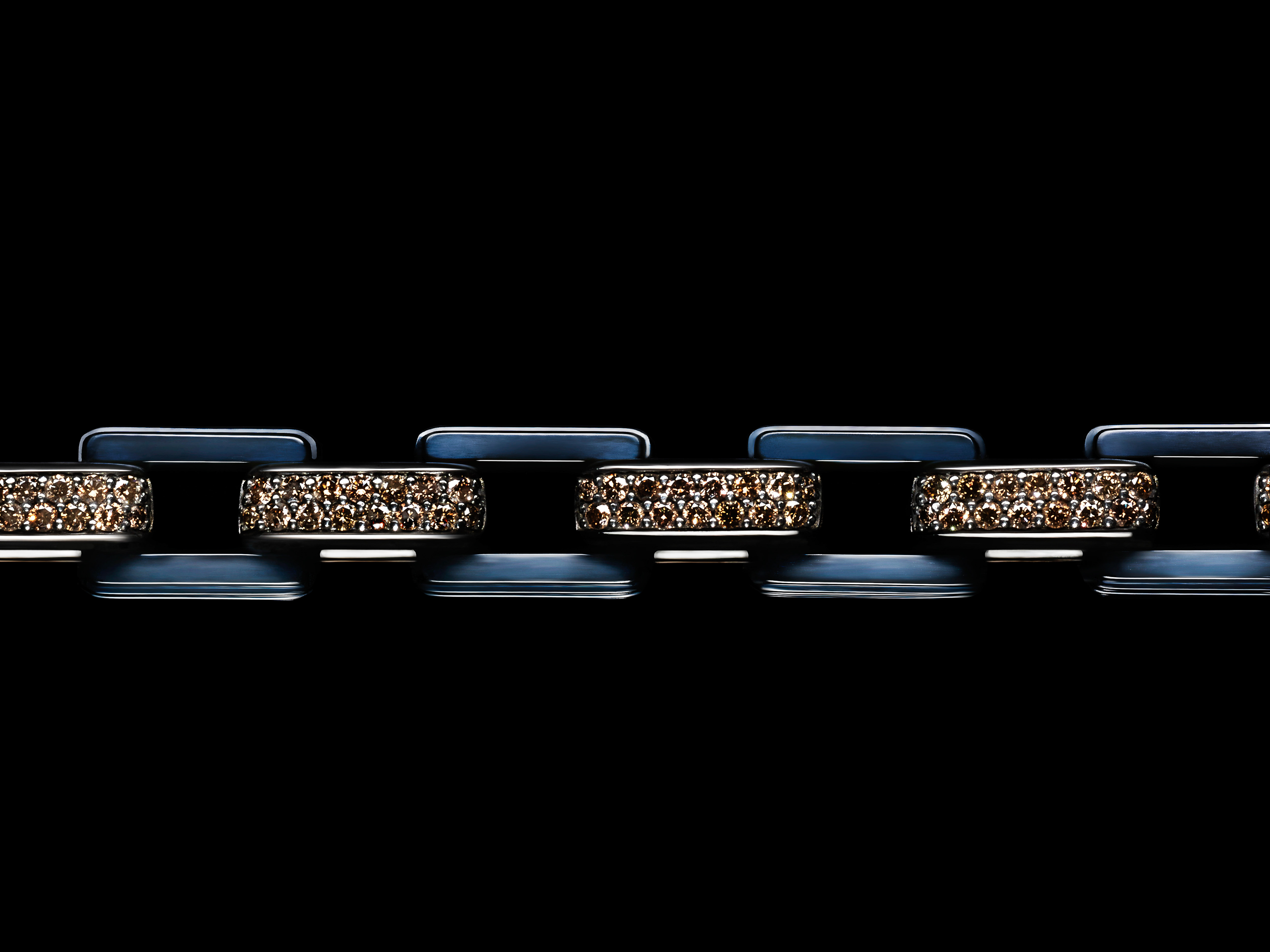 Close-up of a blue and brown jewelry chain on a black background, showcasing its intricate design and alternating colors.