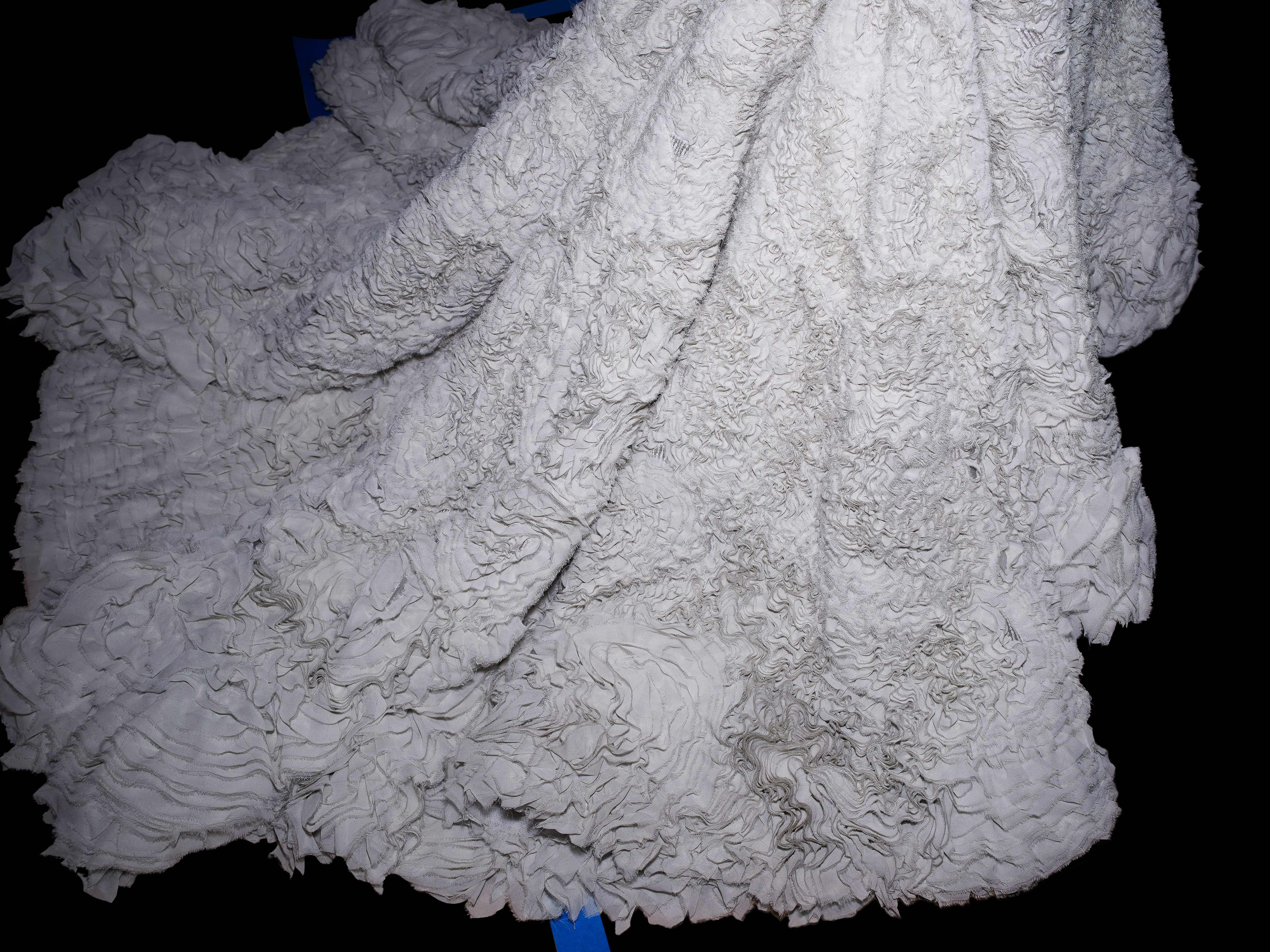 Close-up shot of a textured white textile or fabric with a ruffled pattern, creating a soft and abstract background.