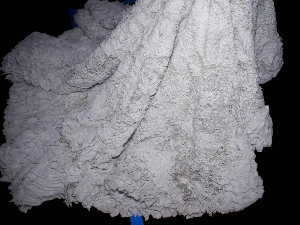 Close-up shot of a textured white textile or fabric with a ruffled pattern, creating a soft and abstract background.