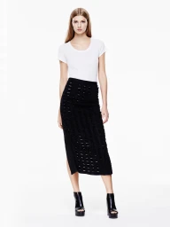 Model wearing a white scoop-neck t-shirt and textured black midi skirt with open-toe platform booties against a white backdrop.