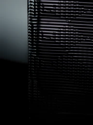 Close-up abstract detail of a dark ridged glass bottle with horizontal grooves and glossy black reflections.
