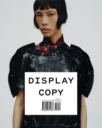 Model with black bob haircut wearing patterned black mandarin collar top against a plain white background
