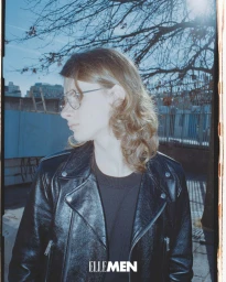 Oskar Marklund in profile wearing a black leather biker jacket and wire-frame glasses for Elle Men Thailand.