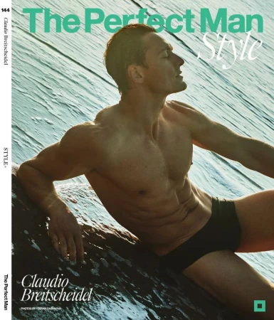Fit adult male with bare torso wearing black swimwear on a rock near ocean water with magazine cover text in a studio shot.